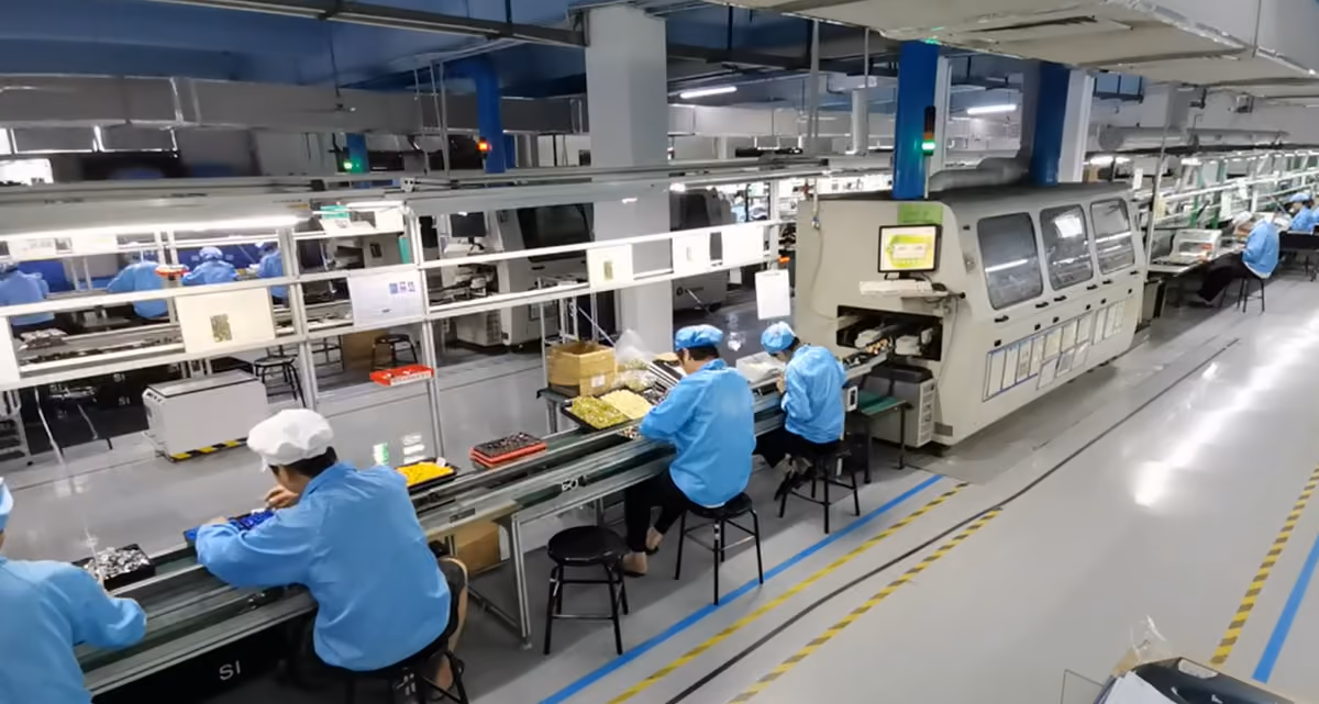 Operators inserting through-hole parts beside a lead-free wave soldering machine